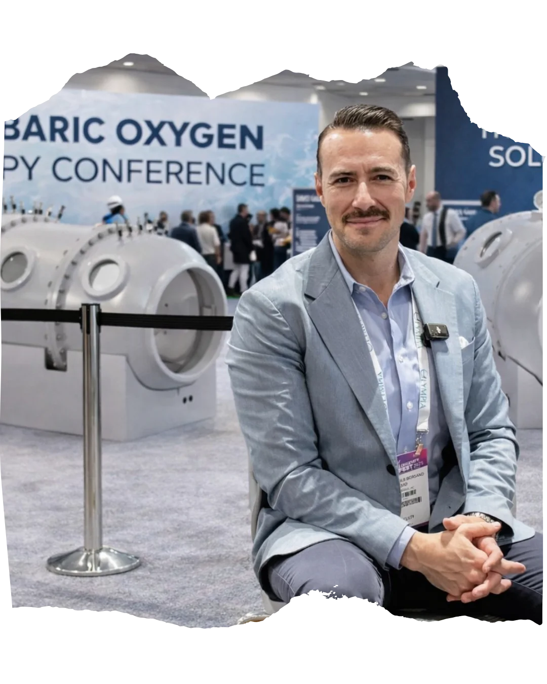 Dr. Alexander Borsand beside hyperbaric equipment at a professional conference