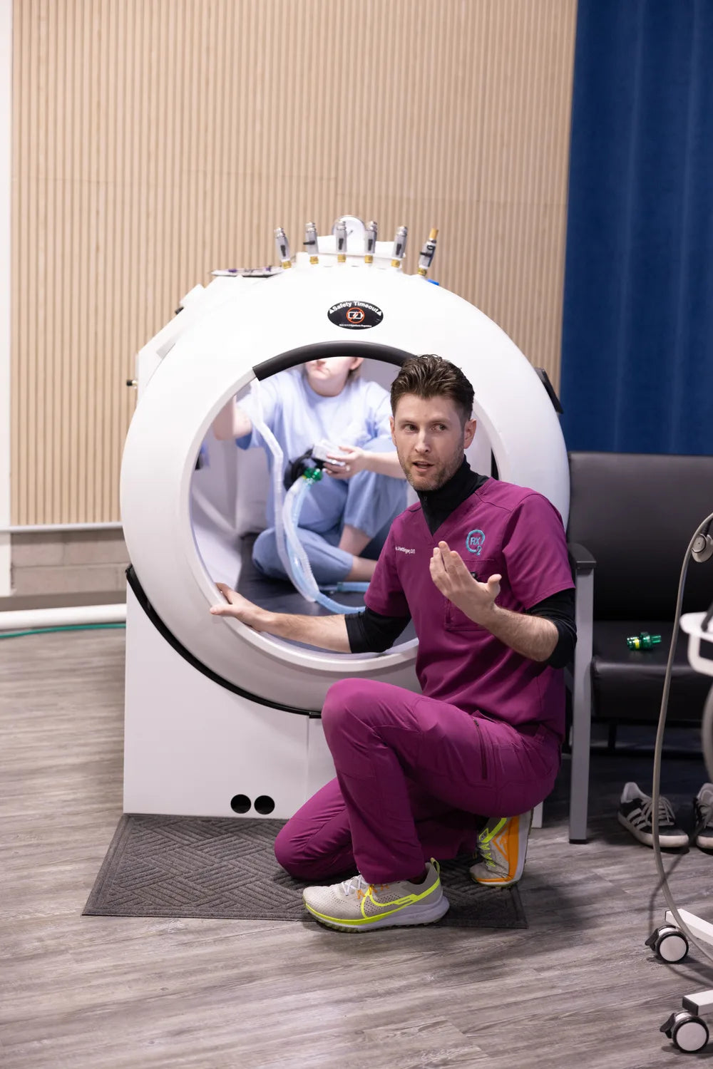 RX-O2 team member explaining treatment beside an open hyperbaric chamber