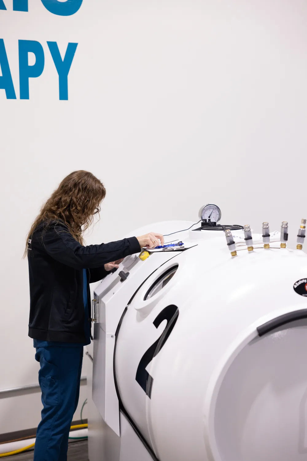 RX-O2 team member reviewing a checklist beside a hyperbaric chamber
